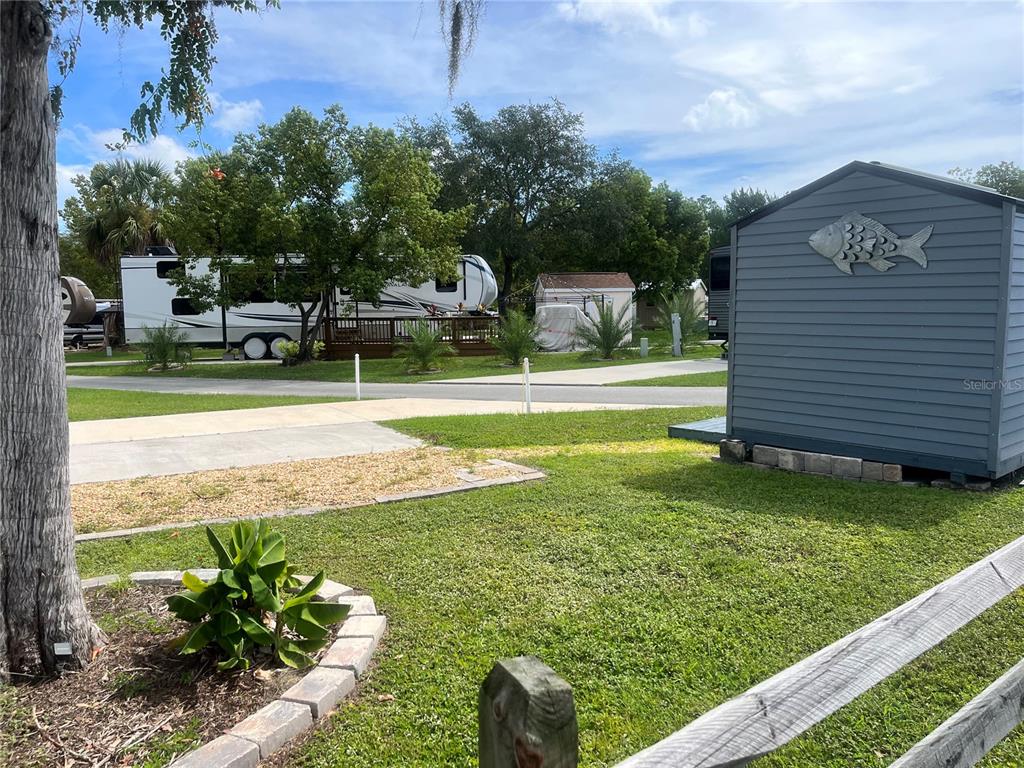 A gray shed with a fish decoration sits on a grassy lot near a parked RV — 2888 NE 102ND TERRACE, SILVER SPRINGS, FL