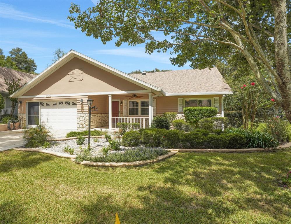 A single-story house with a tan exterior, stone accents, a front porch, and a garage — 8469 SW 92ND PLACE UNIT D, OCALA, FL