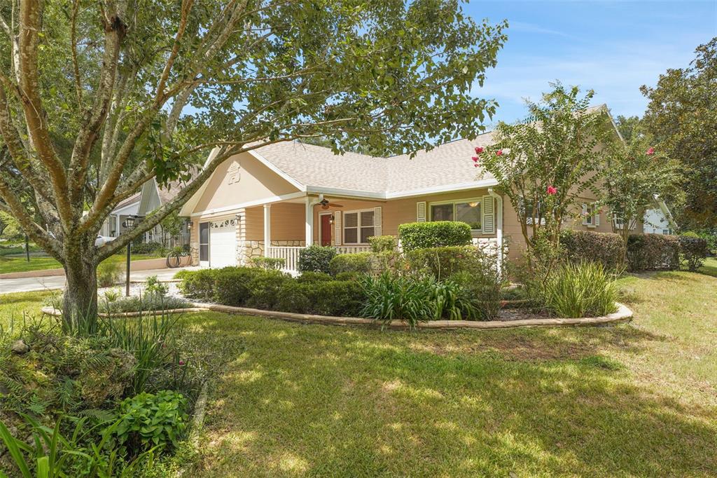 A single-story house with tan siding, a stone facade, and a landscaped front yard — 8469 SW 92ND PLACE UNIT D, OCALA, FL