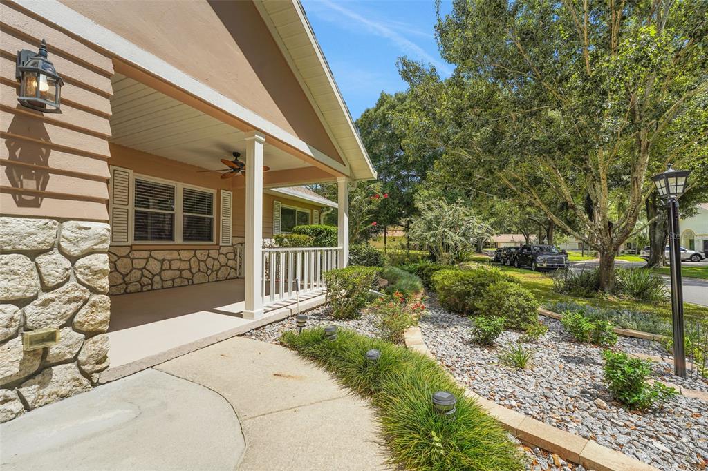 A covered front porch with stone siding and a concrete walkway leads to a landscaped yard — 8469 SW 92ND PLACE UNIT D, OCALA, FL