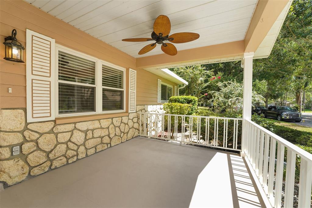 A covered front porch features a stone facade, white railings, and a ceiling fan — 8469 SW 92ND PLACE UNIT D, OCALA, FL