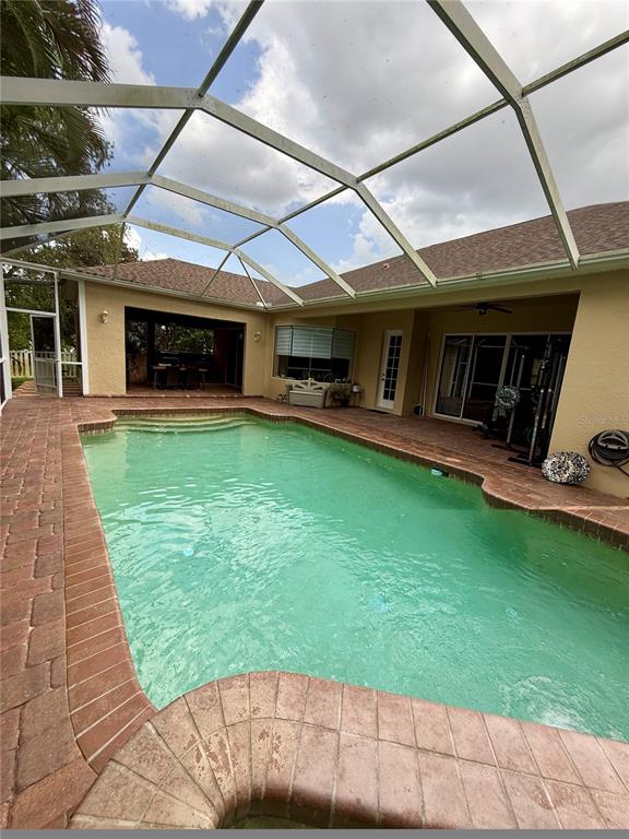 A swimming pool with a brick deck is enclosed by a screened lanai — 11805 SOFT RUSH TERRACE, BRADENTON, FL