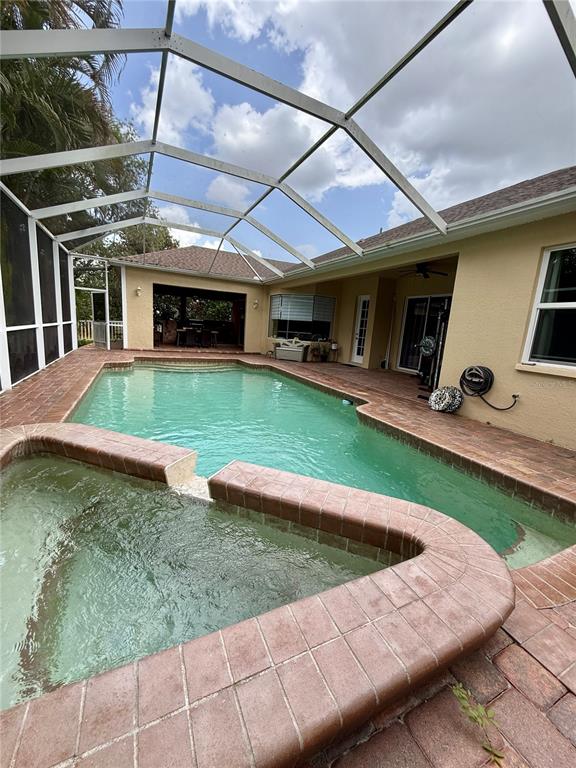 A screened-in patio features a swimming pool, a raised spa, and brick pavers — 11805 SOFT RUSH TERRACE, BRADENTON, FL