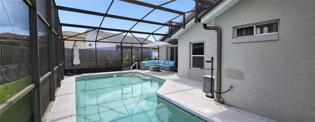 A screened-in patio features a swimming pool, outdoor seating, and a light-colored stucco exterior wall — 1432 AVLEIGH CIRCLE, ORLANDO, FL