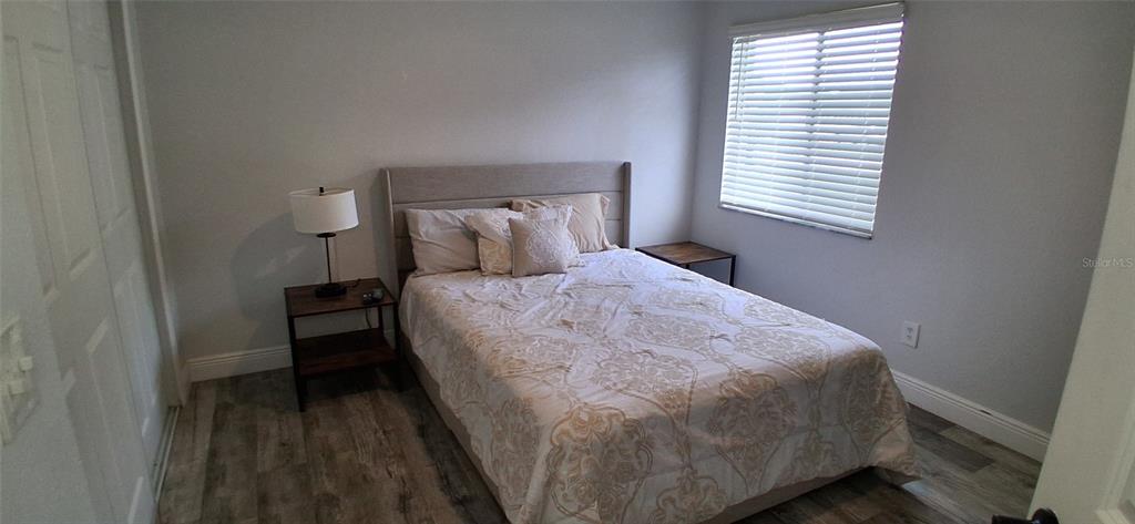 A bedroom features a bed with a patterned comforter, a nightstand, and wood-look flooring — 1432 AVLEIGH CIRCLE, ORLANDO, FL