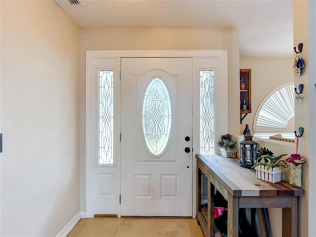 A white front door with oval glass inserts and sidelights sits beside a wooden console table — 4539 MURCROSS LANE, NEW PORT RICHEY, FL