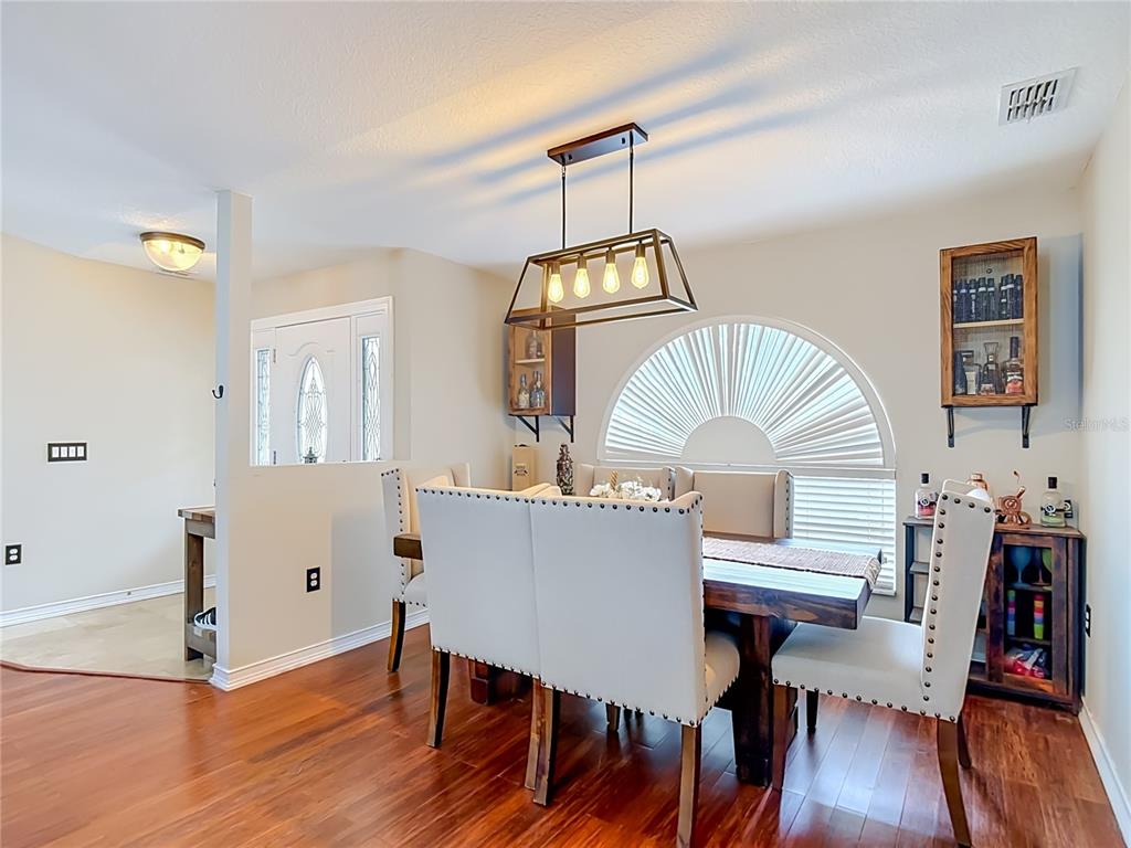 A dining room features a wooden table, upholstered chairs, a rectangular light fixture, and arched windows — 4539 MURCROSS LANE, NEW PORT RICHEY, FL