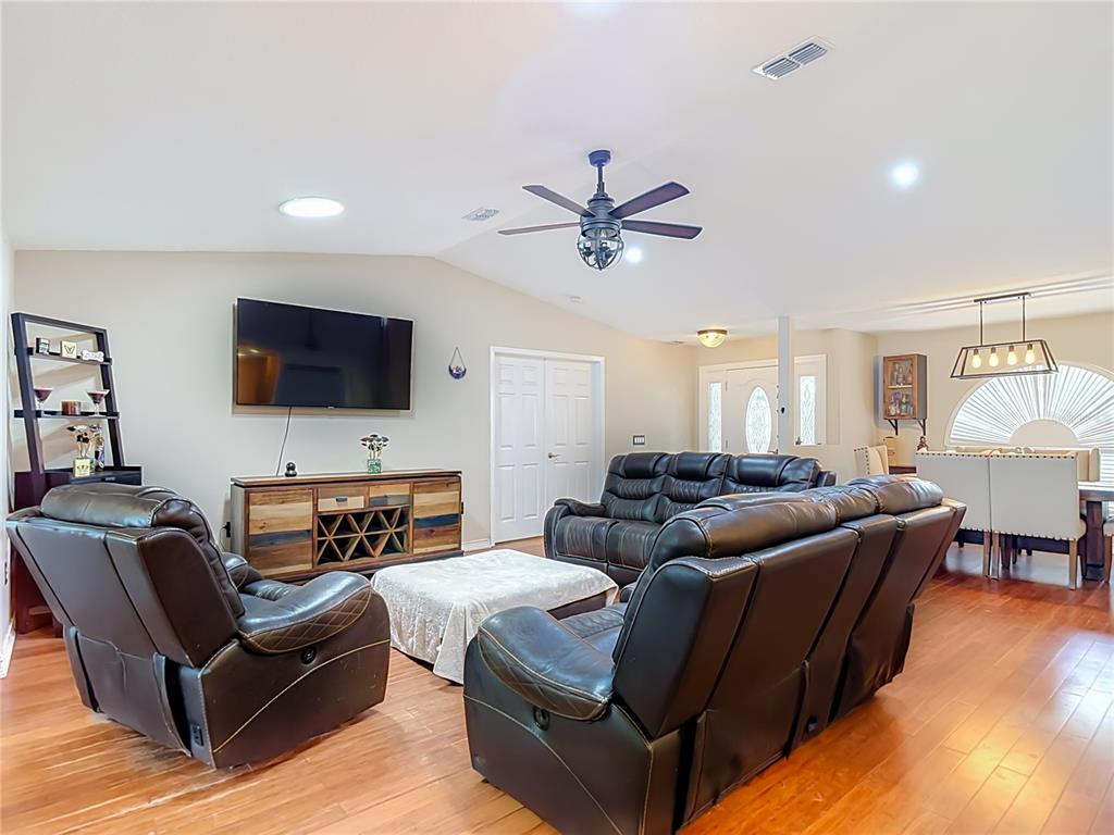 A living room features dark leather furniture, a television, and hardwood flooring — 4539 MURCROSS LANE, NEW PORT RICHEY, FL