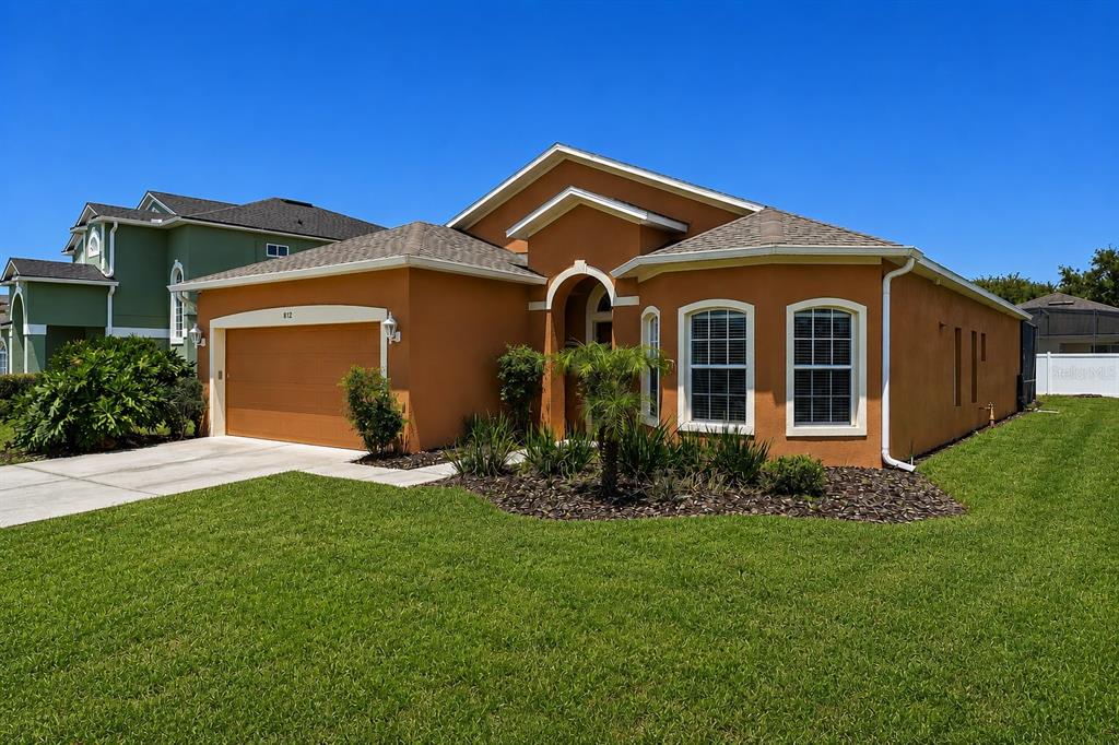 A single-story house with an orange stucco exterior, a two-car garage, and a green lawn — 872 SUSSEX DRIVE, DAVENPORT, FL
