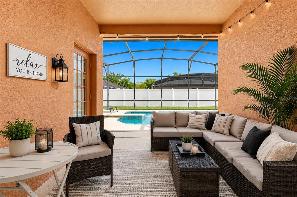 A covered patio features wicker furniture, a rug, and a view of a screened pool — 872 SUSSEX DRIVE, DAVENPORT, FL