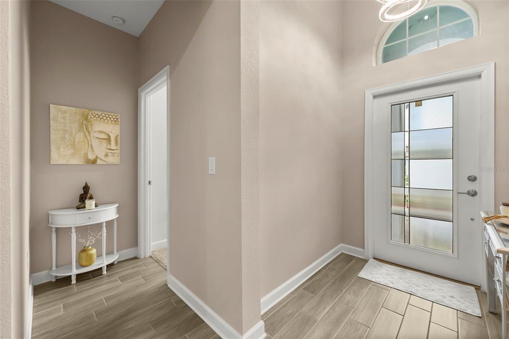 A bright entryway features light wood-look tile flooring, a white front door, and a console table — 2537 CAMDEN PARK CIRCLE, DAVENPORT, FL