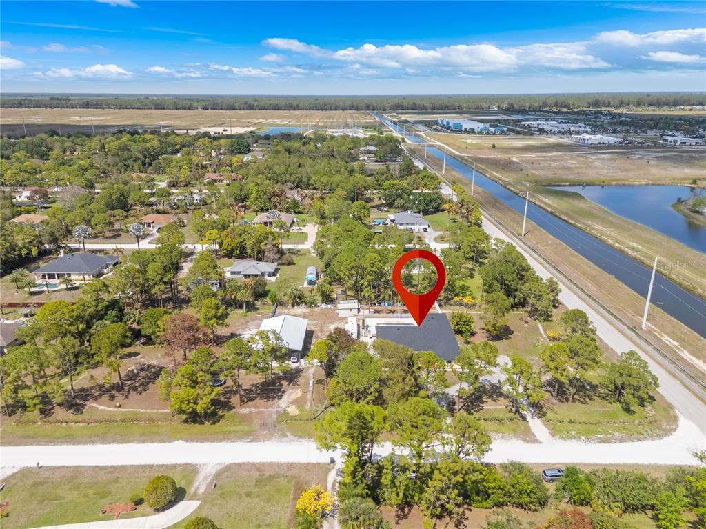 An aerial view shows a house with a dark roof surrounded by trees and land — 17075 ORANGE GROVE BOULEVARD, LOXAHATCHEE, FL