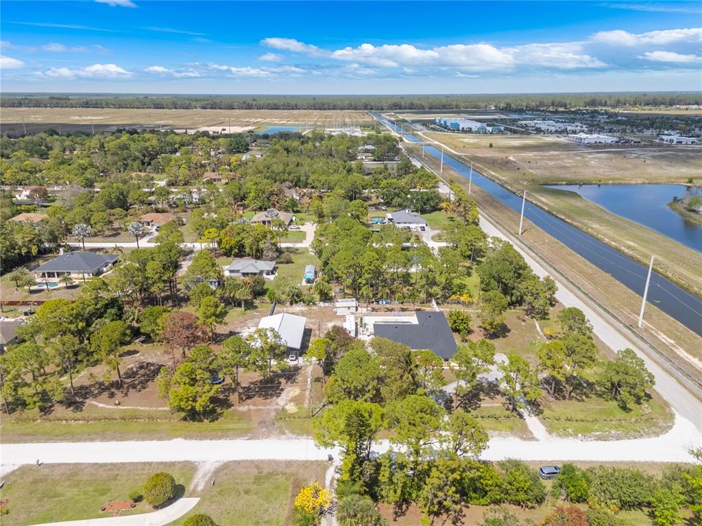 An aerial view shows a residential property with a house, pool, and trees near a canal — 17075 ORANGE GROVE BOULEVARD, LOXAHATCHEE, FL