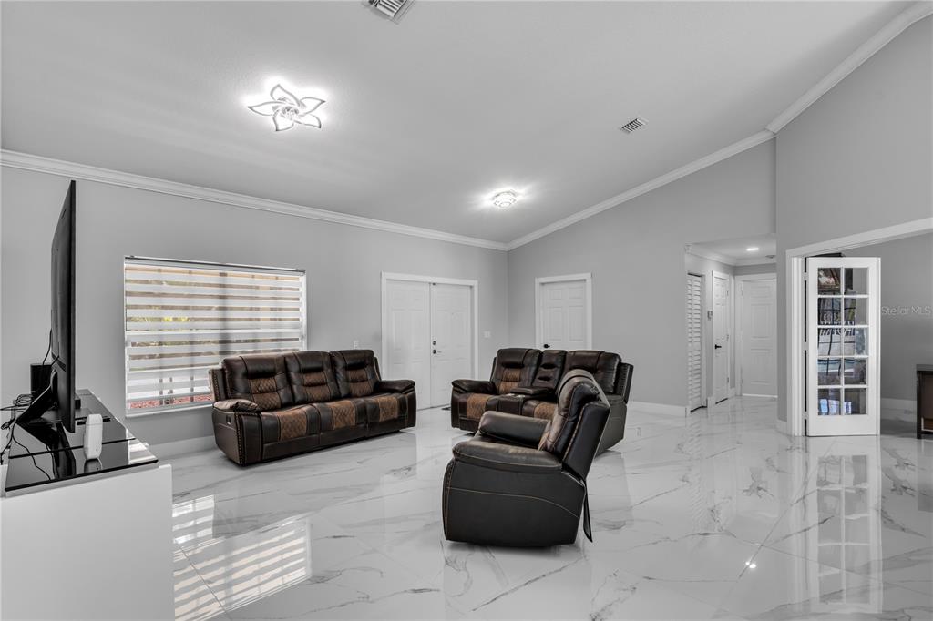 A living room features white marble-look tile flooring, gray walls, and dark leather furniture — 17075 ORANGE GROVE BOULEVARD, LOXAHATCHEE, FL