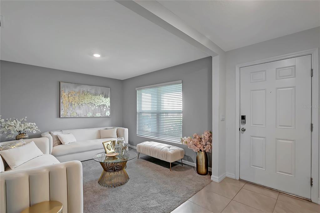 A living room features gray walls, a white sofa, a glass coffee table, and a door — 7737 ROSEWOOD GARDEN LOOP, TAMPA, FL