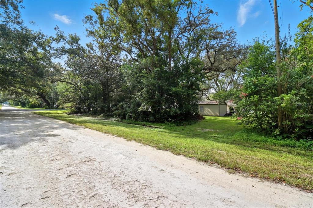 A dirt road runs alongside a grassy lot with mature trees and a small shed — 0 MONROE AVENUE, BROOKSVILLE, FL