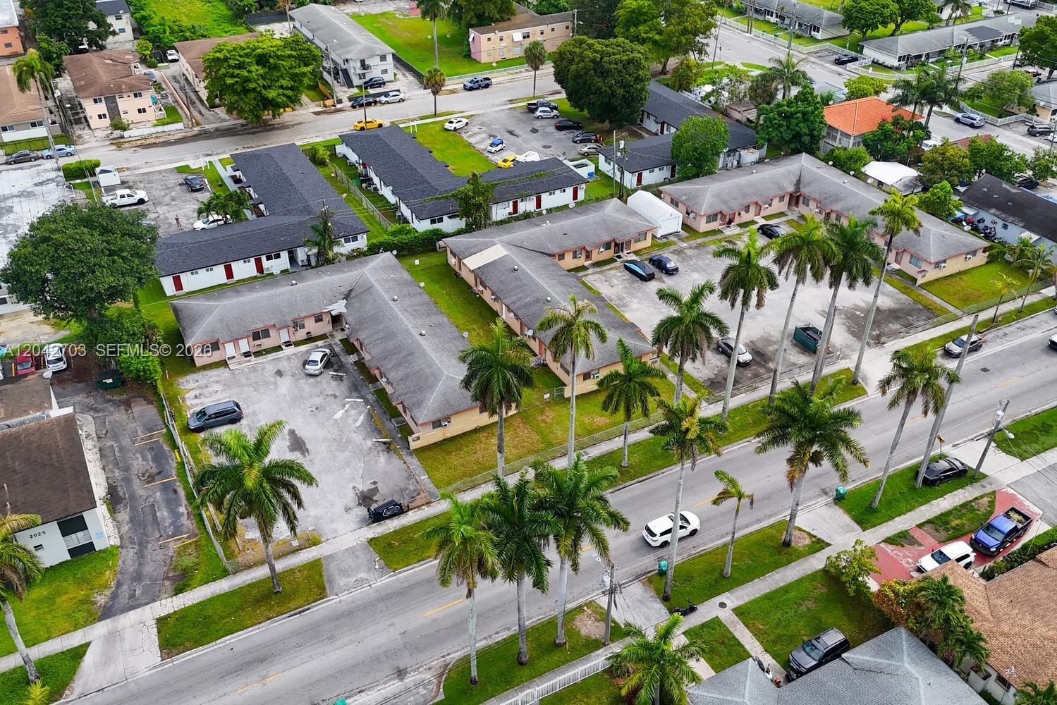 An aerial view shows several single-story apartment buildings with parking lots and palm trees — 1915 NW 28th St, Miami FL 33142, MIAMI, FL