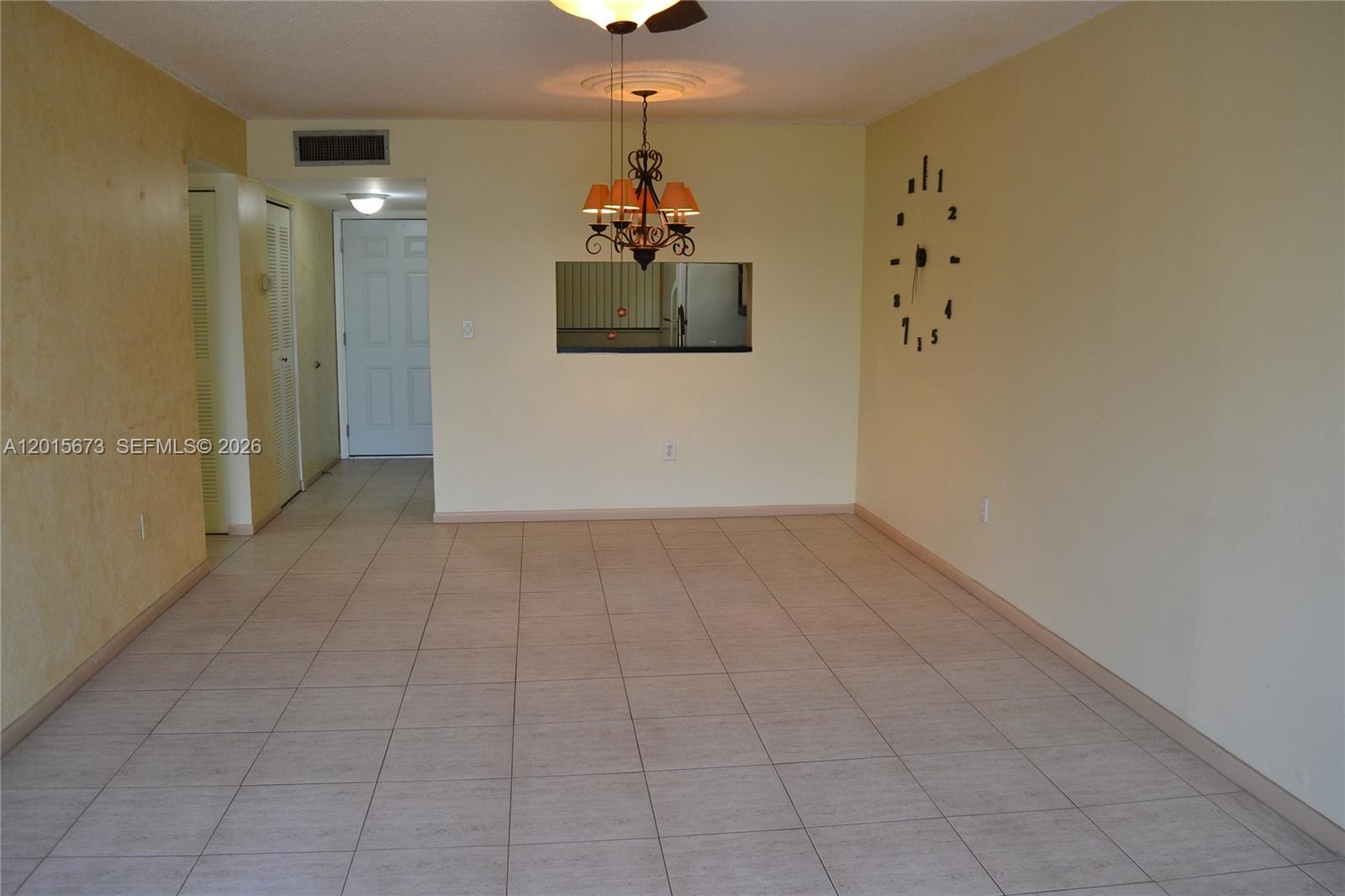 An empty dining room features light tile flooring, a chandelier, and a wall-mounted clock — 10855 SW 112th Ave # 309, Miami FL 33176, MIAMI, FL
