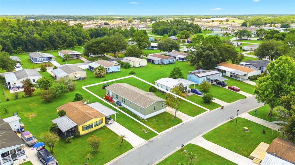 An aerial view shows a light green manufactured home with a white outline on a grassy lot — 209 ELLSWORTH DRIVE, KISSIMMEE, FL