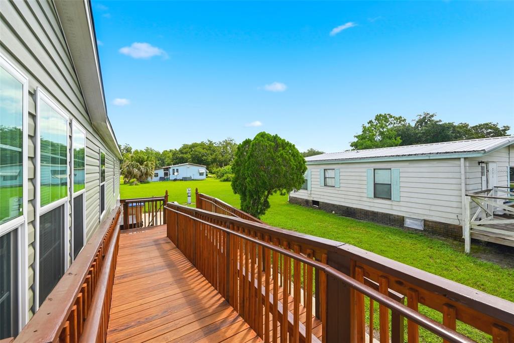 A wooden wheelchair ramp leads along the side of a house toward a grassy yard — 209 ELLSWORTH DRIVE, KISSIMMEE, FL