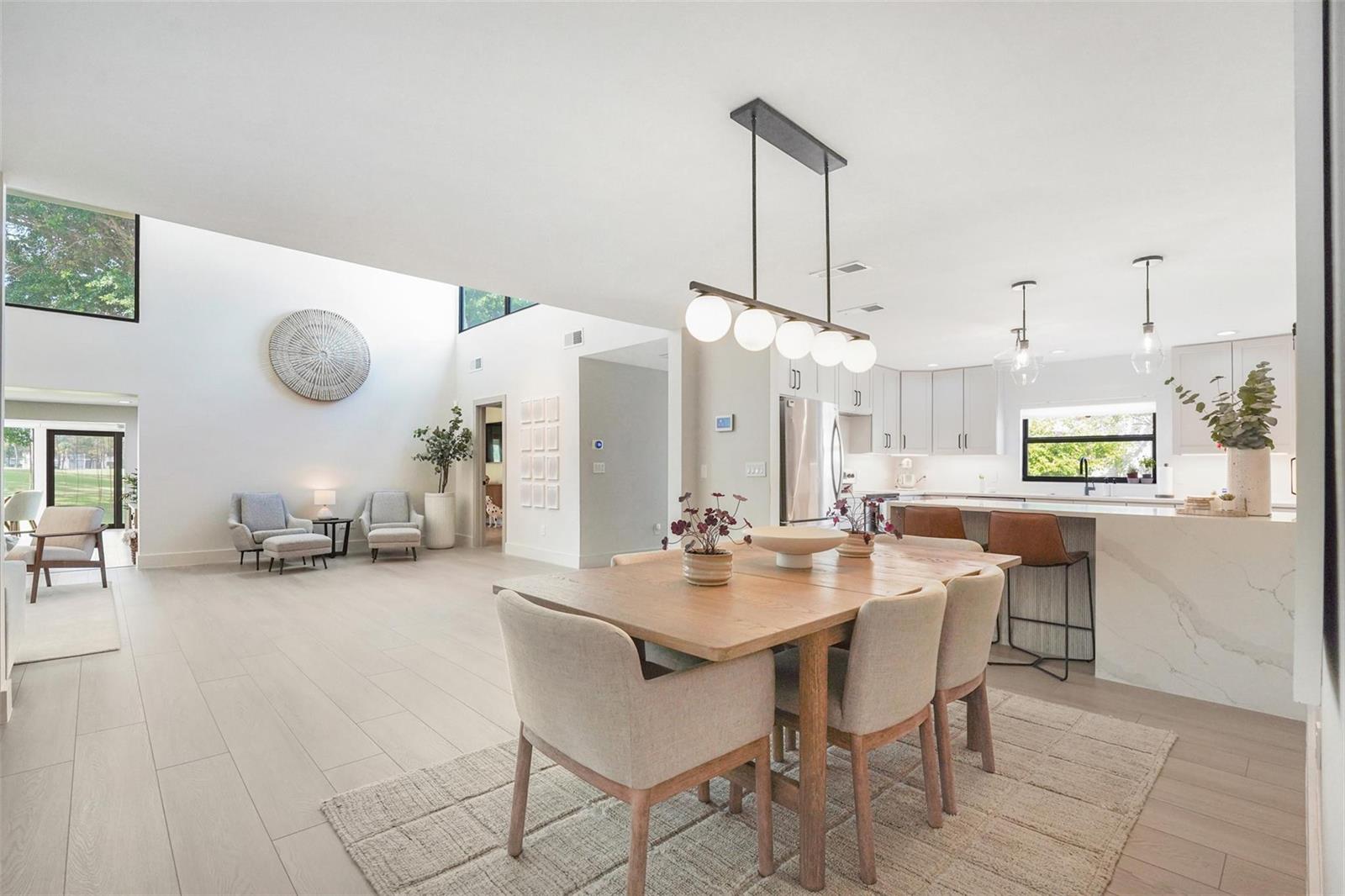 An open-concept dining area and kitchen feature light wood floors, modern lighting, and high ceilings — 8569 Casa Del Lago, Boca Raton FL 33433, BOCA RATON, FL