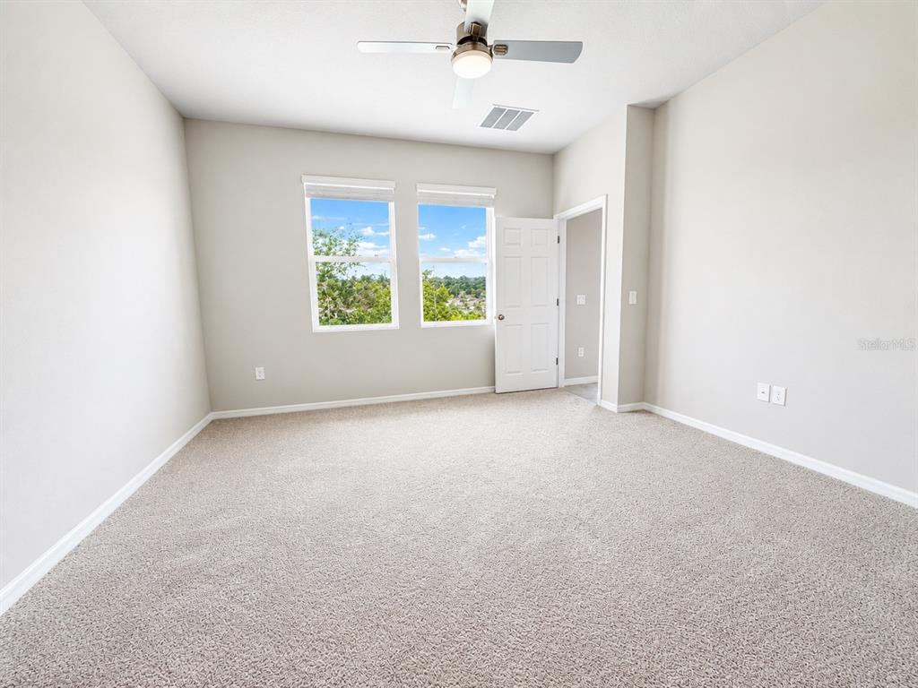 A kitchen with granite countertops and white cabinets opens into a spacious, tiled living area — 2269 MYSTIC MAZE LANE, MINNEOLA, FL