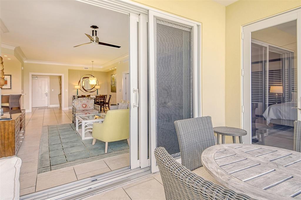 A view from a balcony looking through sliding glass doors into a furnished living room — 915 SEASIDE DRIVE UNIT 606, Weeks 14-17, SARASOTA, FL