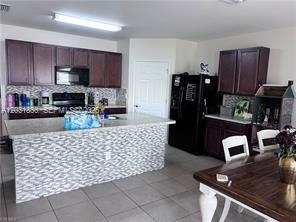 A kitchen features dark wood cabinets, a tiled island, and black appliances — 3815 SW 11th Pl, Cape Coral FL 33914, CAPE CORAL, FL