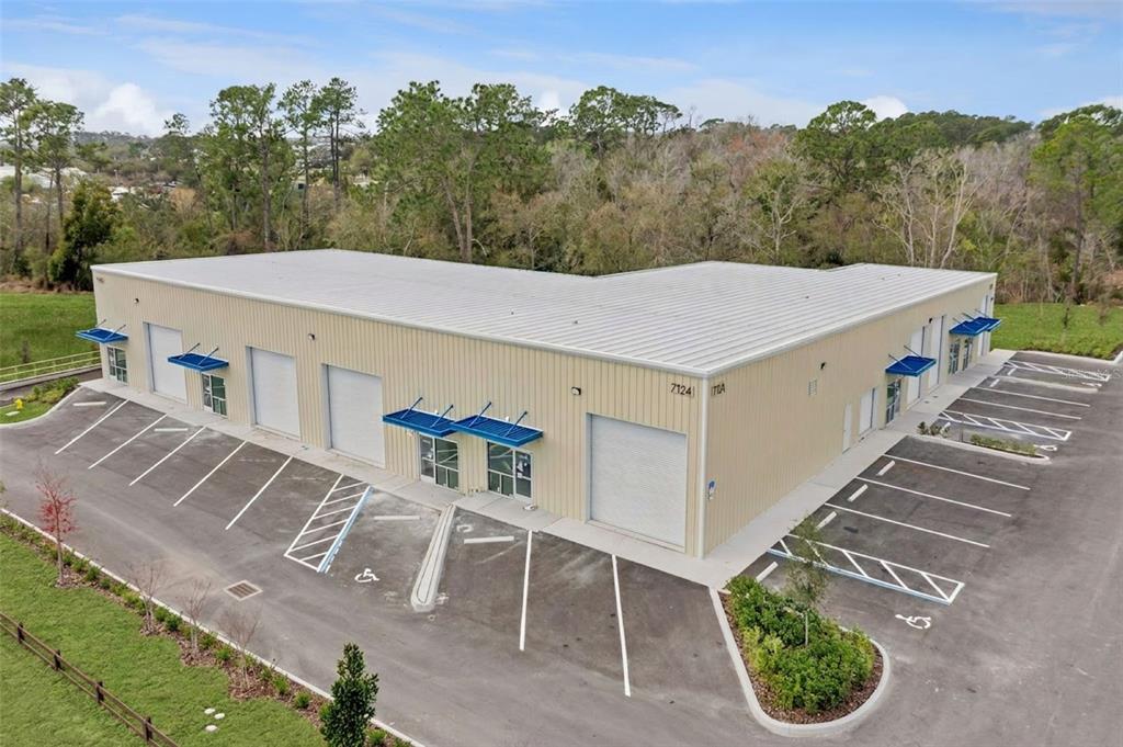 An aerial view of a tan metal industrial building with multiple roll-up doors and parking — 7120 SAMPEY ROAD UNIT 103, GROVELAND, FL