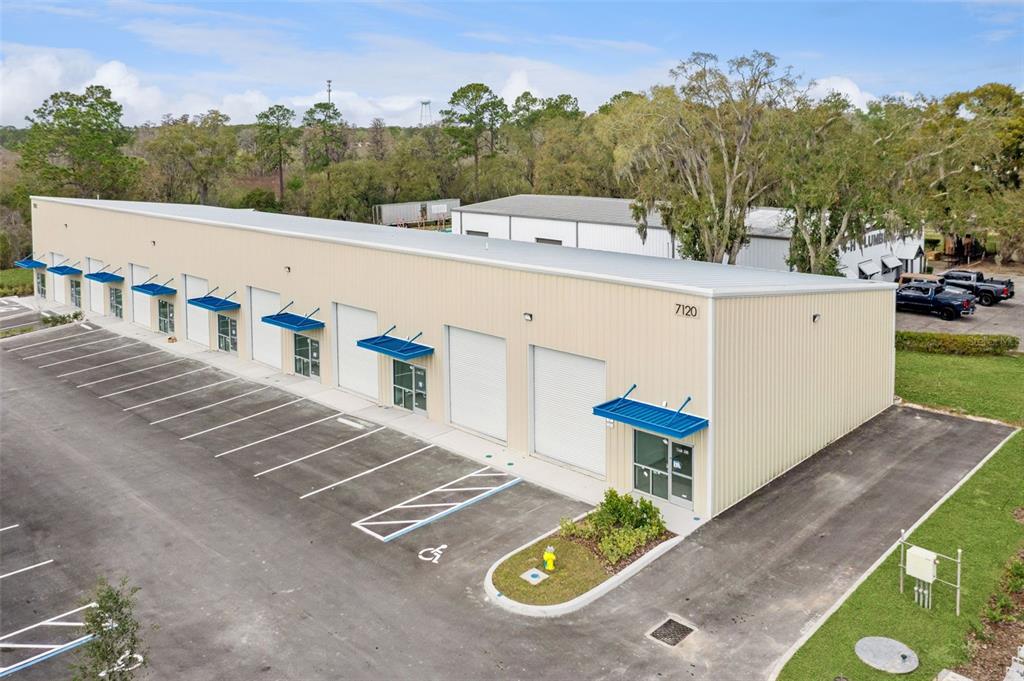 An aerial view shows a long, tan industrial warehouse building with multiple roll-up doors — 7120 SAMPEY ROAD UNIT 103, GROVELAND, FL
