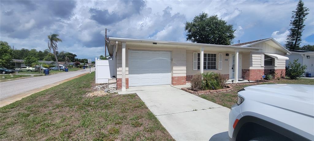 A single-story house with a white garage door, brick accents, and a concrete driveway — 3243 BAYPORT DRIVE, HOLIDAY, FL