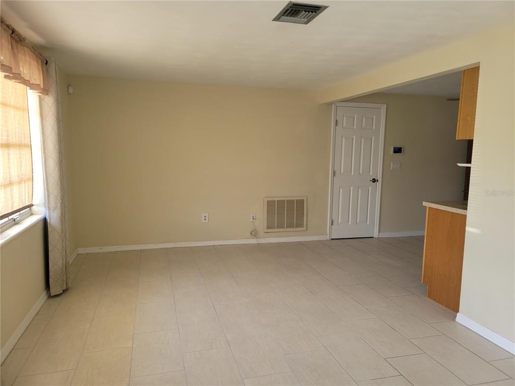 An interior view of a room with light-colored tile flooring, beige walls, and a white door — 3243 BAYPORT DRIVE, HOLIDAY, FL