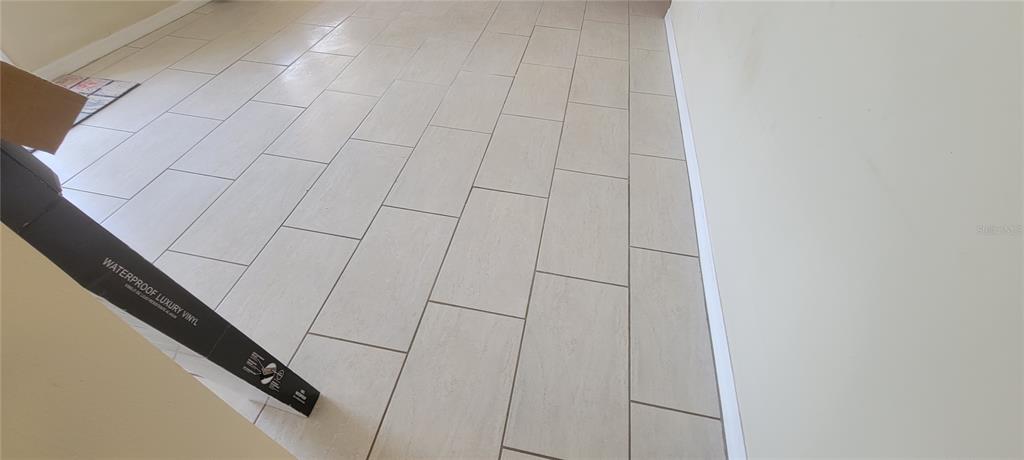 A room with light-colored rectangular floor tiles and white baseboards — 3243 BAYPORT DRIVE, HOLIDAY, FL