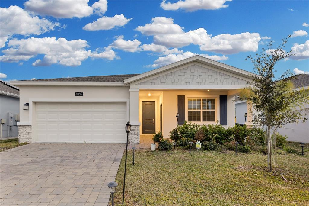A single-story house with a paved driveway, two-car garage, and a covered front entryway — 3087 CAMDEN WAY, DAVENPORT, FL