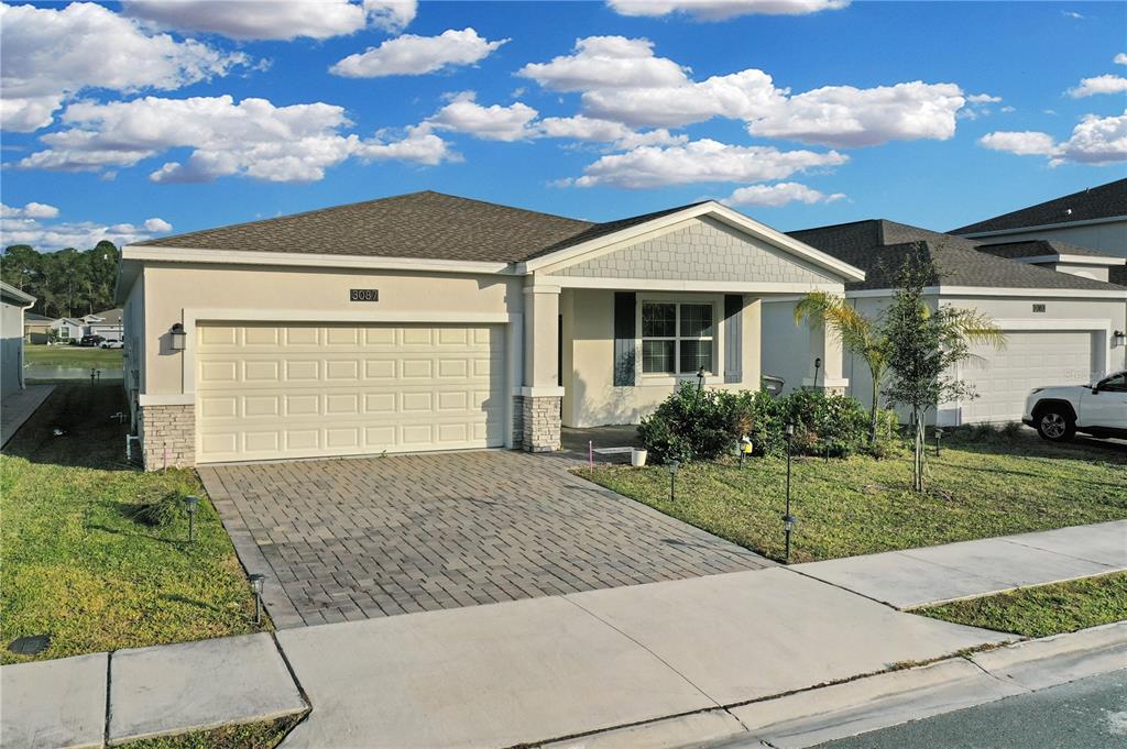 A single-story suburban house features a paved driveway, a two-car garage, and a front porch — 3087 CAMDEN WAY, DAVENPORT, FL
