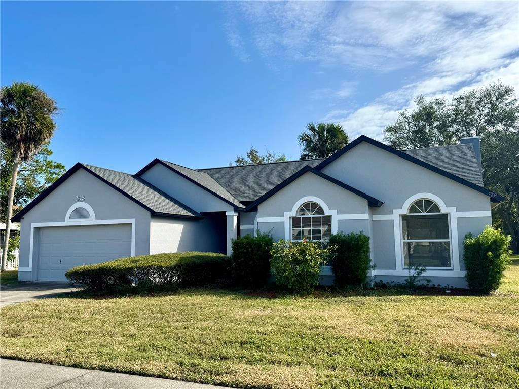 A single-story house with a gray exterior, dark roof, and two arched windows — 215 HOLLOWBROOK CIRCLE, DAYTONA BEACH, FL