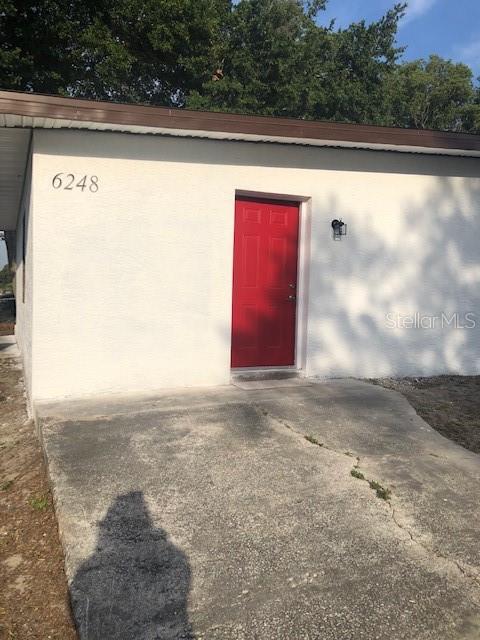 A white exterior wall features a bright red door and the house number 6248 — 6246-6248 20TH STREET, ZEPHYRHILLS, FL