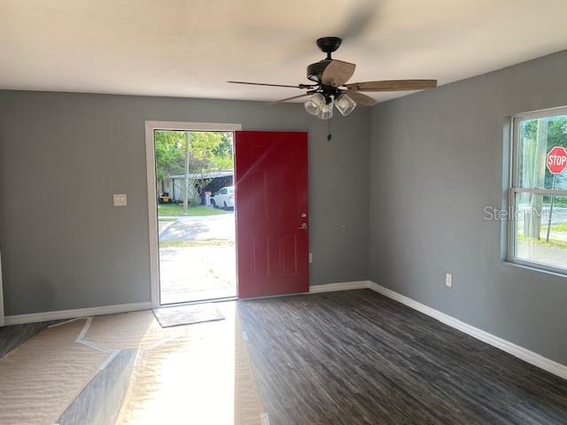 A room with gray walls, wood-look flooring, a ceiling fan, and a red front door — 6246-6248 20TH STREET, ZEPHYRHILLS, FL