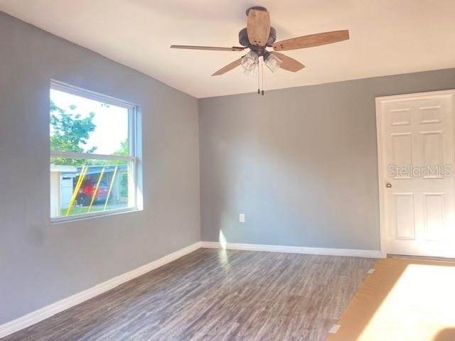 A bedroom with gray walls, wood-look flooring, a ceiling fan, and a white door — 6246-6248 20TH STREET, ZEPHYRHILLS, FL