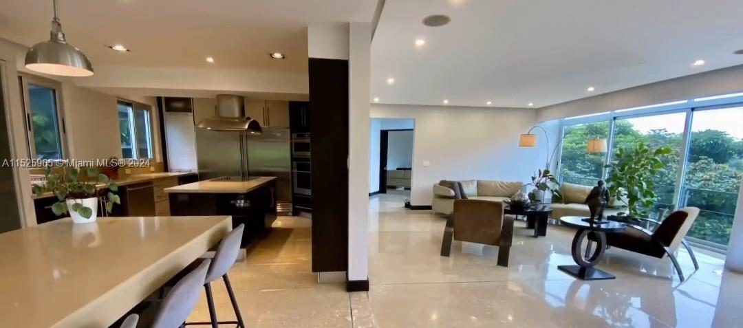 An open-concept kitchen and living area feature light tile floors, modern cabinetry, and floor-to-ceiling windows — Eco Residencial Vila Real Pozos de Santa Ana, SJ, SJ