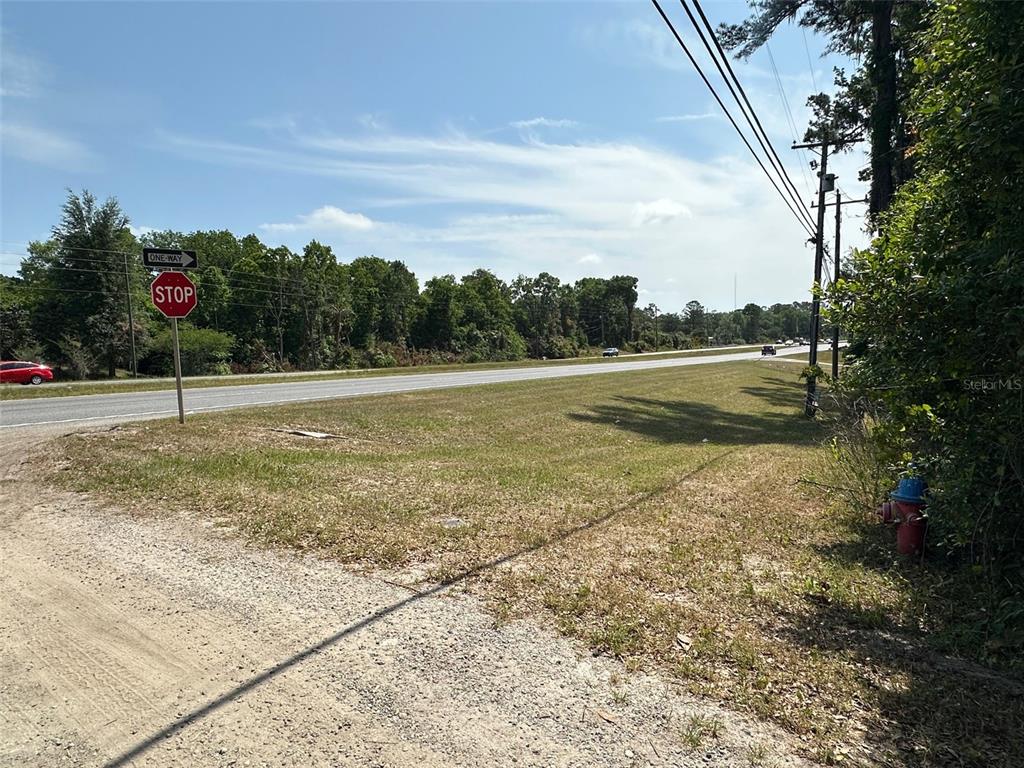 A grassy roadside lot features a stop sign, a fire hydrant, and utility poles — 12100 NW US HIGHWAY 441, GAINESVILLE, FL
