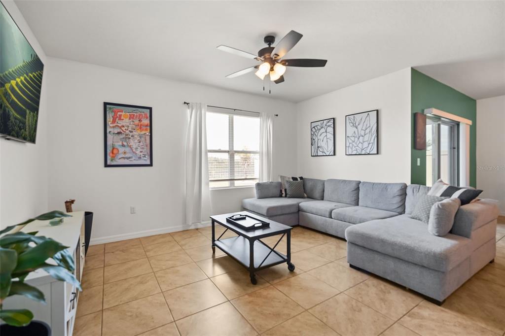 A living room features a grey sectional sofa, a coffee table, and tile flooring — 860 BROOKLET DRIVE, DAVENPORT, FL