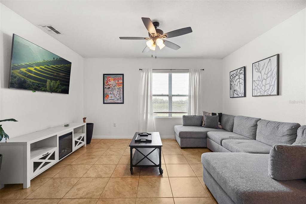 A living room features a gray sectional sofa, a television, and tile flooring — 860 BROOKLET DRIVE, DAVENPORT, FL