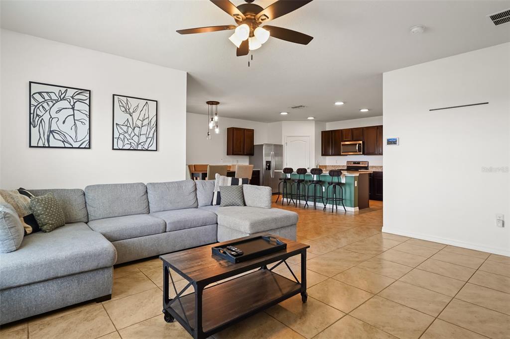 A living room with a gray sectional sofa opens into a kitchen with bar seating — 860 BROOKLET DRIVE, DAVENPORT, FL