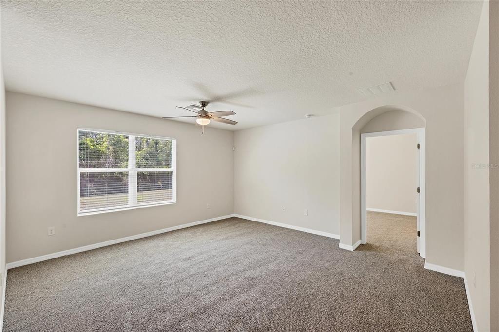 A carpeted bedroom features a ceiling fan, a window with blinds, and an arched doorway — 153 TIERRA VERDE WAY, BRADENTON, FL