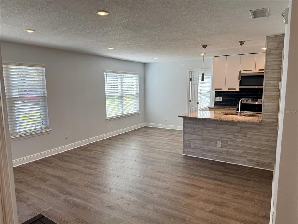 An open-concept living area features wood-look flooring, recessed lighting, and a kitchen with a breakfast bar — 2585 GRASSY POINT DRIVE UNIT 111, LAKE MARY, FL