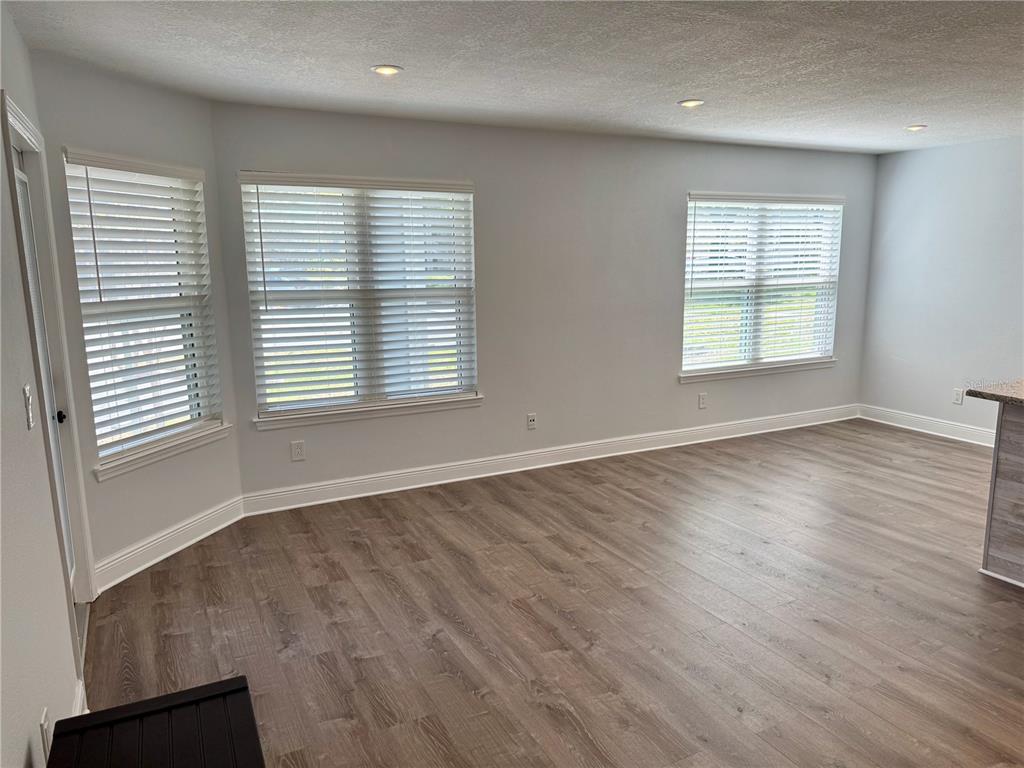 An empty room with light gray walls, wood-look flooring, and three windows with white blinds — 2585 GRASSY POINT DRIVE UNIT 111, LAKE MARY, FL