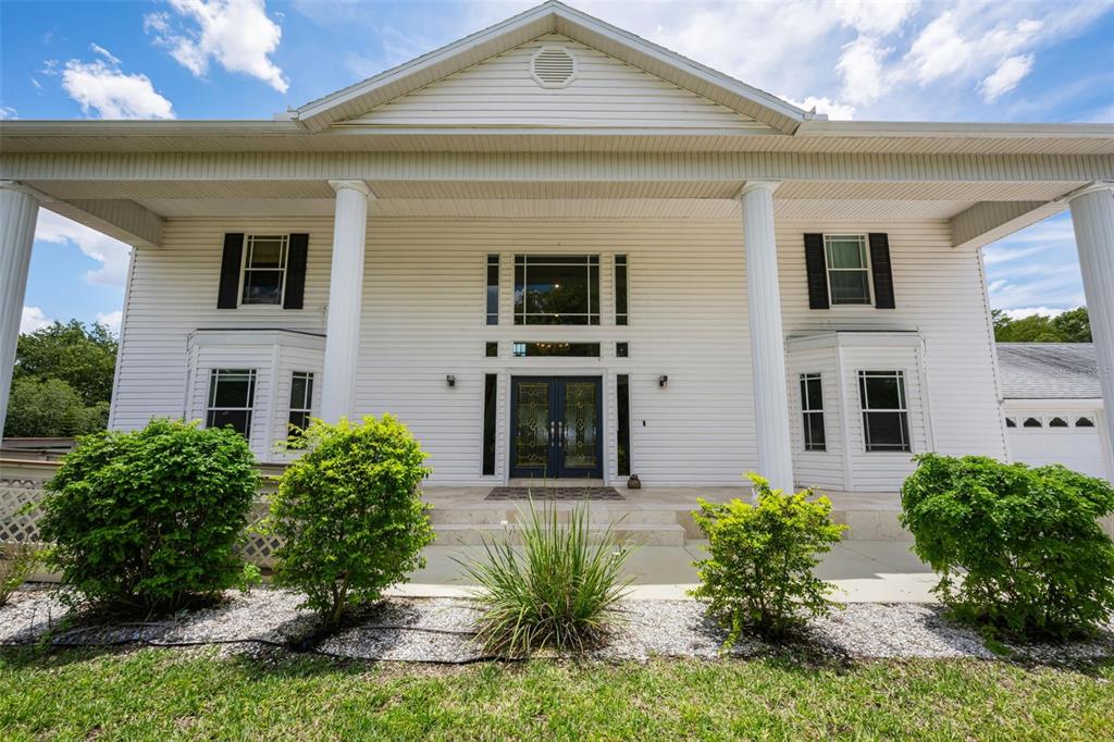 A two-story white house with a columned front porch and a central double-door entrance — 11046 LAKEVIEW DRIVE, NEW PORT RICHEY, FL