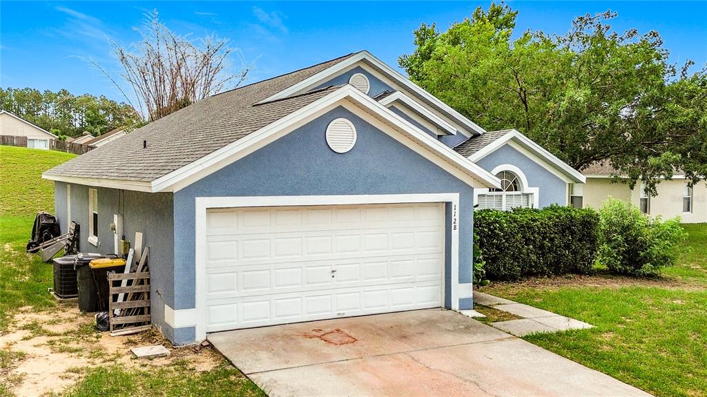 A blue single-story house features a two-car garage and a concrete driveway — 1128 PINEDALE DRIVE, DAVENPORT, FL