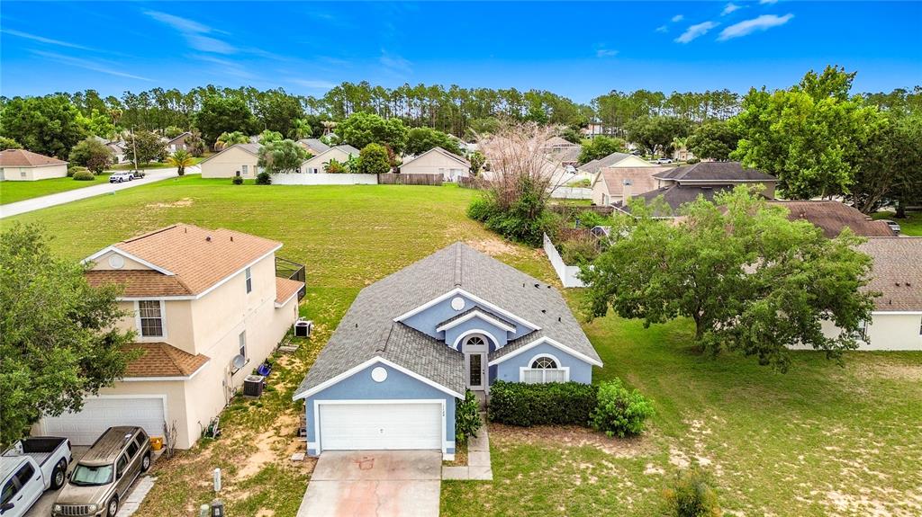An aerial view shows a blue single-story house with a garage next to a two-story home — 1128 PINEDALE DRIVE, DAVENPORT, FL